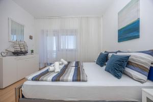 a large bed in a white room with blue pillows at Casa Vita in Dramalj