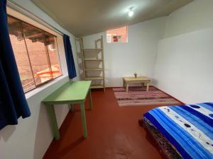 a bedroom with a bed and a desk and a window at Raíz Azul in Pisac