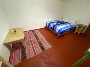 a room with two beds and a table and rug at Raíz Azul in Pisac
