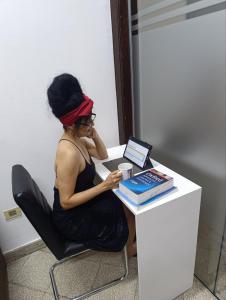 a woman sitting at a desk talking on a cell phone at Cuba Linda Capsule Stay in Asunción
