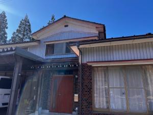 a house with a front porch and a red door at HAPPY MAGIC guesthouse in Tateyama