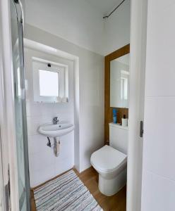 a white bathroom with a toilet and a sink at Yellow Guesthouse in Faro