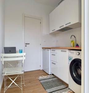 a white kitchen with a washer and dryer in it at Yellow Guesthouse in Faro +14 photos