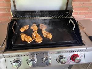 a grill with four pieces of meat cooking on it at Private king suite in Dubuque