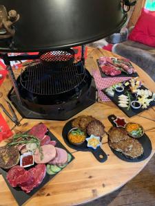a table with plates of food next to a grill at Le chalet des Cambuses in Saint Die