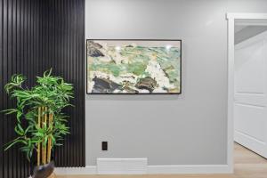 a painting hanging on a wall next to a plant at Mountain Escape Deluxe King Suite-Free Parking in Cochrane
