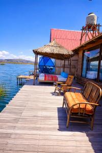 a wooden dock with chairs and a house on the water at Uros Killa Lodge in Puno +53 photos