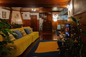 a living room with a yellow couch and blue pillows at Casa da Lala - Alojamento a 4km de Fátima in Fontainhas