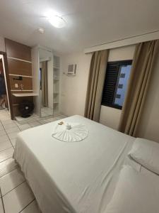 a white bed in a room with a bathroom at Flats Beira Mar in Caraguatatuba