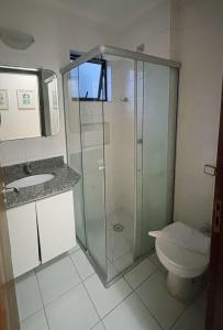 a bathroom with a glass shower and a toilet at Flats Beira Mar in Caraguatatuba