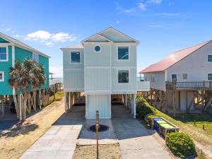 a house on the beach next to some houses at Oceanfront Luxury Private Steps to Beach New in Oak Island
