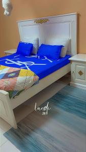 a bed with blue pillows on it in a room at Zac Mbao appartement en face de la place in Mbaw