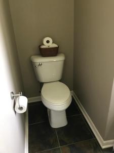 a bathroom with a toilet with a basket of toilet paper at Private king suite in Dubuque