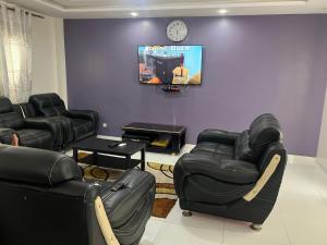 a living room with black leather chairs and a tv at Zac Mbao appartement en face de la place in Mbaw