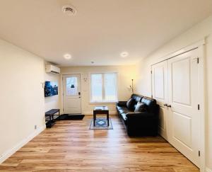 a living room with a black couch and a table at New Guesthouse in Charlottetown