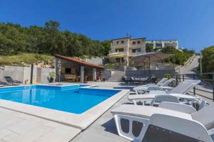 a swimming pool with white chairs and an umbrella at Apartment in Hreljin 39448 in Hreljin