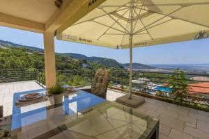 a patio with a glass table and an umbrella at Apartment in Hreljin 39448 in Hreljin