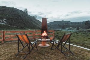 two chairs and a fire pit in a field at Te Awa Glamping in Taumarunui