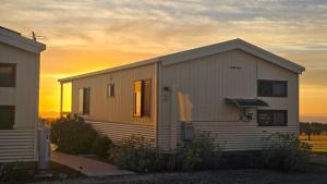 a small white house with the sunset in the background at OMARU FARM STAY in Ventnor