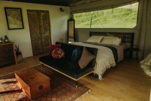 a bedroom with a bed and a couch and a window at Te Awa Glamping in Taumarunui