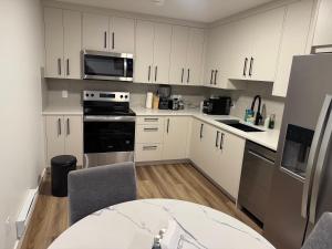 a kitchen with white cabinets and stainless steel appliances at 5 Star Suite with Free Parking and Easy Access to Downtown in Calgary
