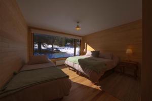 a bedroom with two beds and a window at Cuyul Lodge in Malalcahuello