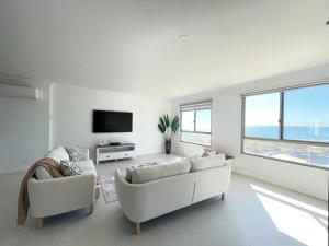 a white living room with two couches and a television at Coastal Calm Seascapes unit 3 in Falcon