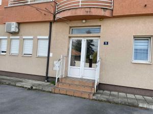 a house with a white door and stairs in front at SkyBreak Apartment in Ledine