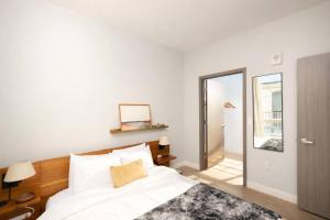a white bedroom with a bed and a mirror at Charming Walker's Point Apt with Balcony | Sleeps 4 in Milwaukee