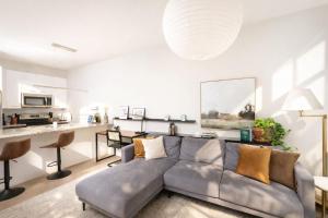 a living room with a gray couch and a kitchen at Charming Walker's Point Apt with Balcony | Sleeps 4 in Milwaukee