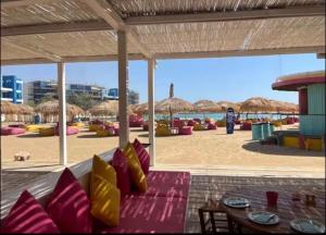 a patio with a couch and tables and straw umbrellas at Ayla golf in Aqaba