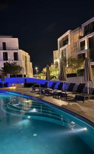 a swimming pool with chairs and umbrellas at night at Ayla golf in Aqaba