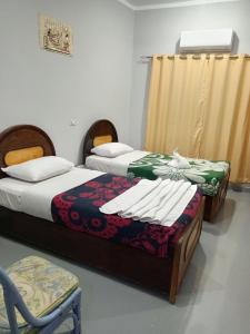 a bedroom with two beds and a chair at Bob marley luxor in Luxor