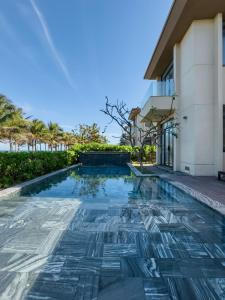 a swimming pool in front of a building at Lumina Villas Cam Ranh, Bai Dai beach luxury resort villas in Cam Ranh
