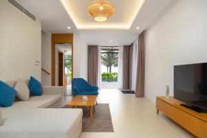 a living room with a couch and a tv at Lumina Villas Cam Ranh, Bai Dai beach luxury resort villas in Cam Ranh