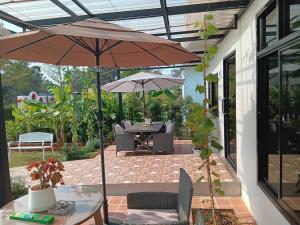 a patio with an umbrella and a table and chairs at แอนนา เรสซิเดนซ์ in Ban Dung