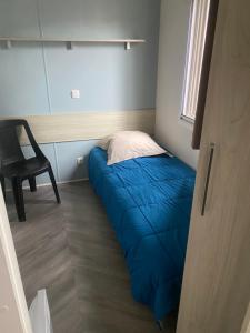 a small bedroom with a blue bed and a chair at Résidence des dunes de Contis in Saint-Julien-en-Born