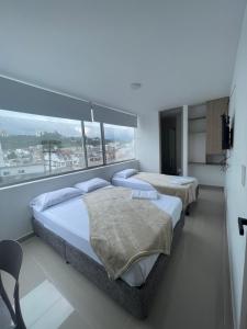 two beds in a room with a large window at Hotel Portal Del Cerro Manizales in Manizales