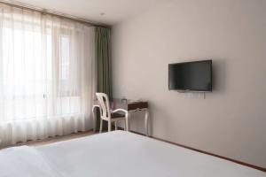 a bedroom with a bed and a desk and a tv at Kaboting Hotel Chongqing Prime Location Near Jiefangbei & Hongya Cave, 1 Minute Walk to Metro, Ideal for International Guests,Free Self-Service Laundry, Free High-Speed WiFi,Free Chinese Tea, Free Travel Advice in Chongqing