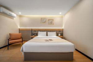 a bedroom with a large bed and a chair at Kaboting Hotel Chongqing Prime Location Near Jiefangbei & Hongya Cave, 1 Minute Walk to Metro, Ideal for International Guests,Free Self-Service Laundry, Free High-Speed WiFi,Free Chinese Tea, Free Travel Advice in Chongqing