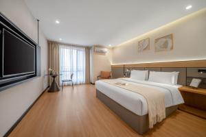 a hotel room with a large bed and a flat screen tv at Kaboting Hotel Chongqing Prime Location Near Jiefangbei & Hongya Cave, 1 Minute Walk to Metro, Ideal for International Guests,Free Self-Service Laundry, Free High-Speed WiFi,Free Chinese Tea, Free Travel Advice in Chongqing