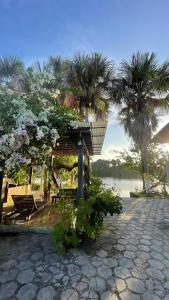 a pavilion with chairs and trees and a body of water at Chalé Marinas in Barreirinhas