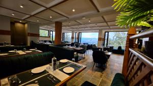 a restaurant with green chairs and tables and windows at Jeeva Premium Rooms in Dalhousie