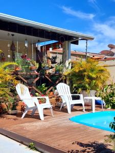 three white chairs sitting on a deck next to a pool at Casa JB in Chapada dos Guimarães