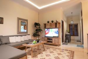 a living room with a couch and a tv at Sabi House Lesmana in Timuran