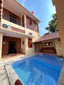 a swimming pool in front of a house at Sabi House Lesmana in Timuran