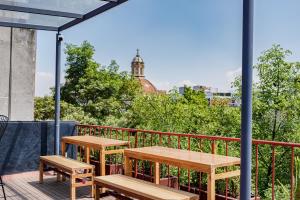 zwei Tische und Bänke auf einem Balkon in der Unterkunft Comfort Luxe Loft near Bellas Artes casaXúla in Mexiko-Stadt