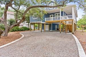 a house with a tree and a gravel driveway at Live Oak Cottage OKI Beach Retreat in Oak Island