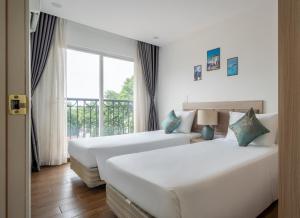two beds in a hotel room with a window at Luxe Paradise Hotel Truc Bach in Hanoi