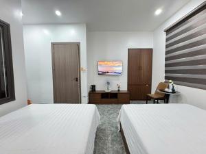 a bedroom with two beds and a desk with a chair at Khách Sạn MoonKnight 2 in Sầm Sơn